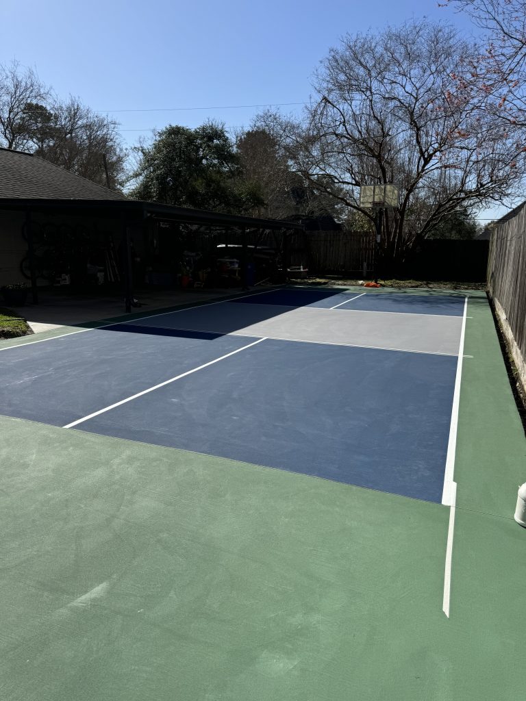 A residential blue and grey pickleball court built into a driveway, combining function and fun in a smart space-saving design.