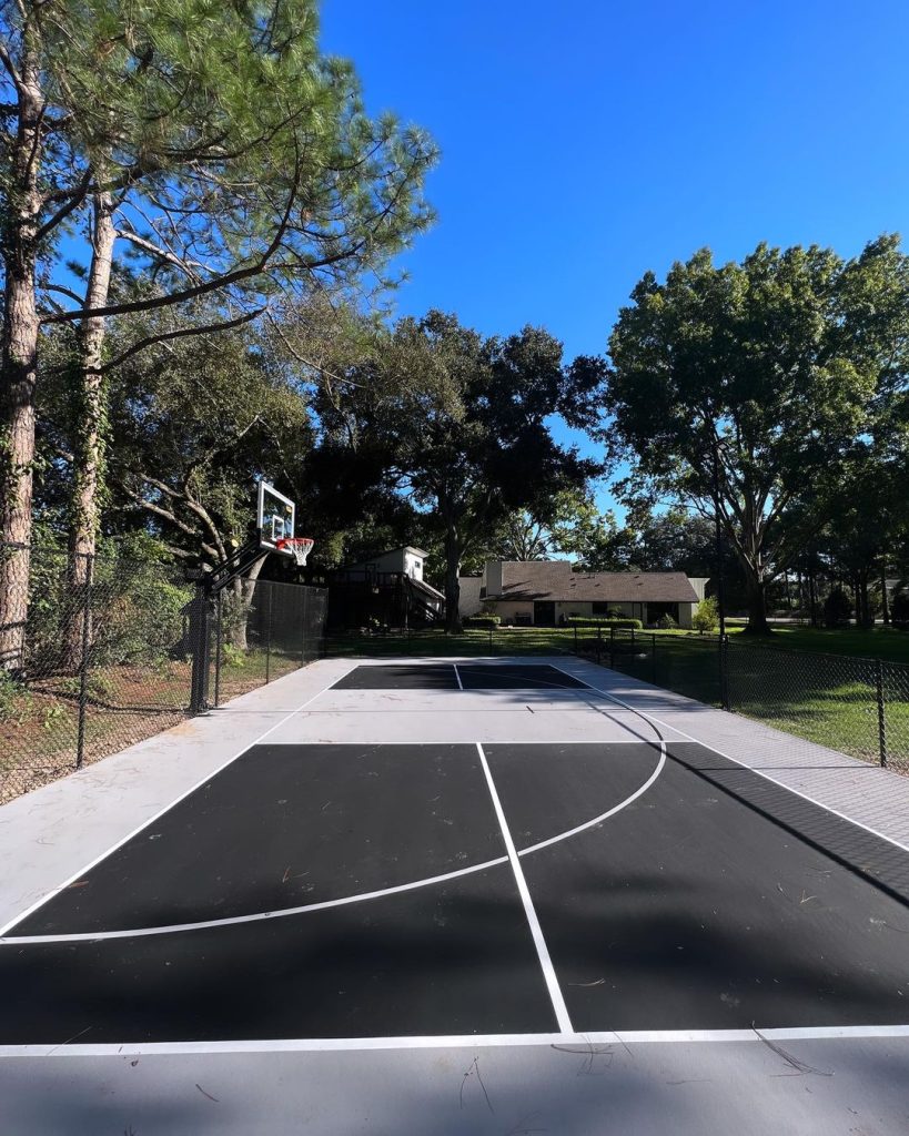 Black and white multi-use pickleball court with fencing and installed nets