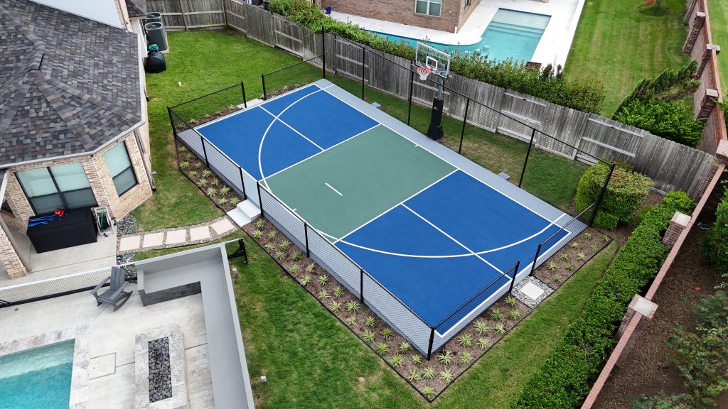 Multi-court with blue, grey, and white lines featuring a half-court basketball hoop and pickleball setup installed in Sugar Land, Tex