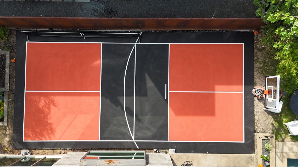Custom multi sport court in Houston, TX with red and black surfacing, lined for basketball and pickleball, built for an NFL athlete.
