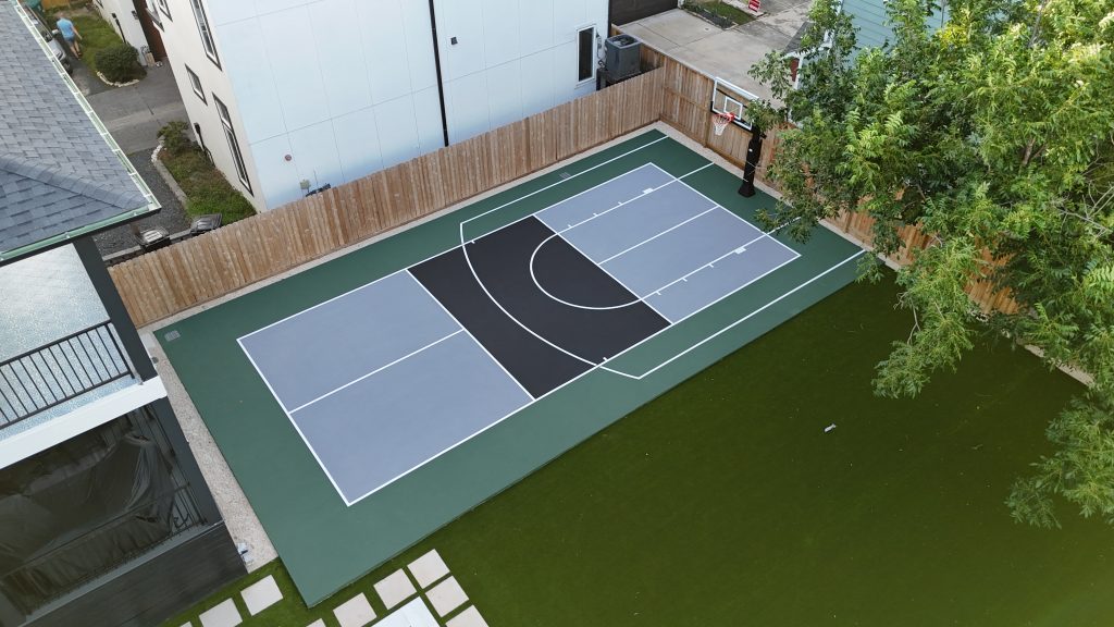 Custom backyard basketball and pickleball court combo in Houston, Texas with acrylic surface and in-ground hoop beside a residential patio.