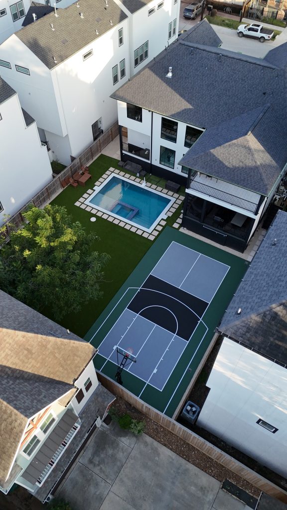 Multi-sport backyard court in Houston featuring a custom basketball half-court with pickleball lines, built on a concrete surface with acrylic coating.