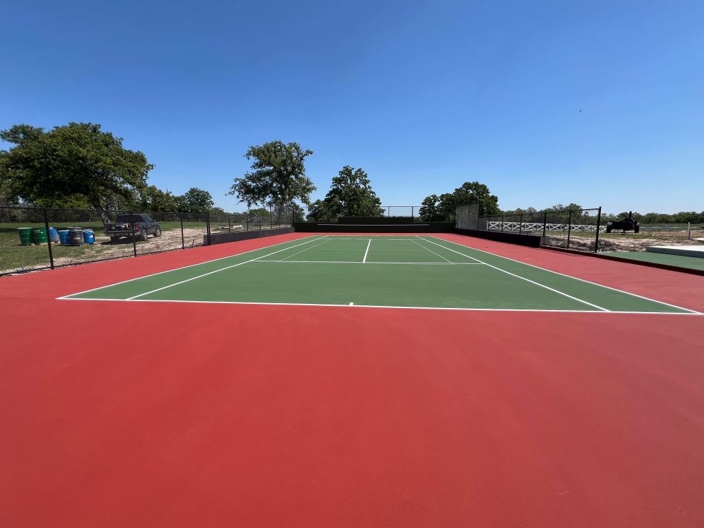 Letterbed TX multi sport court with custom red and green surfacing, black vinyl fencing, and painted tennis, pickleball, and basketball lines