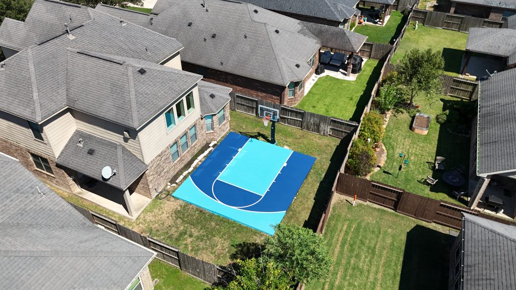 Outdoor mini basketball court in Fulshear TX | Backyard basketball court installation with custom logos and colors