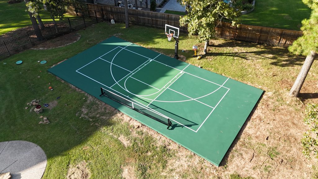 Modern backyard multi-sport court with basketball hoop and pickleball setup in Magnolia, Texas.