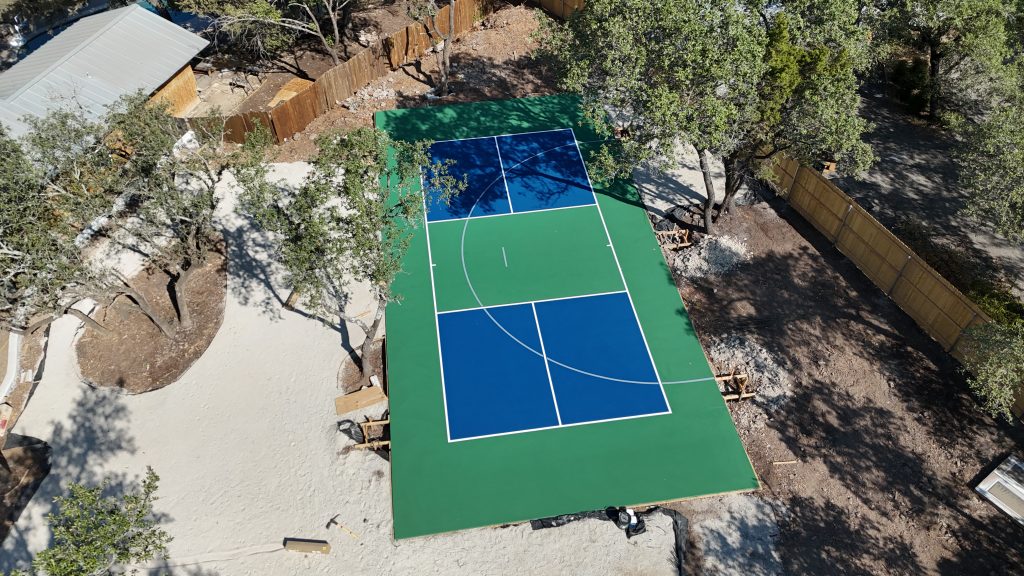 Freshly surfaced backyard basketball and pickleball court with blue and green colorway in Austin, Texas.